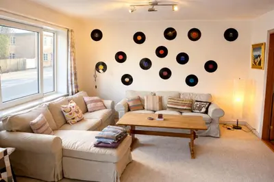 a living room with a couch and records on the wall at Cozy House Close to Beach and B&O in Struer