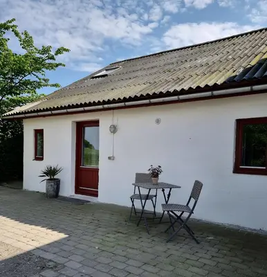 a table and chairs in front of a white house at Calm and idyllic surroundings in Northen Jutland in Nibe