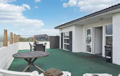 a patio with a table and chairs on a roof at Stunning Home In Løkken With Sauna in Løkken