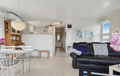 a living room with a black leather couch and a table at Stunning Home In Løkken With Sauna in Løkken