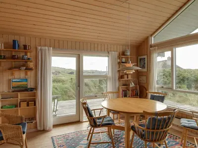 a dining room with a table and chairs and a window at Holiday Home Eunike - 220m from the sea by Interhome in Løkken