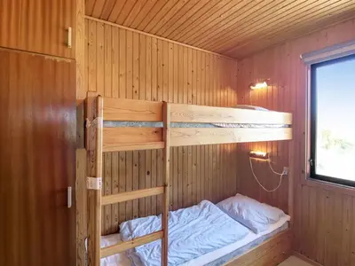 a bedroom with two bunk beds in a wooden cabin at Holiday Home Mira - 375m from the sea by Interhome in Løkken