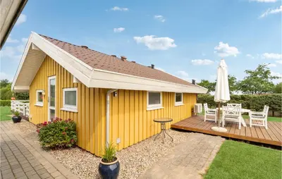 a yellow house with a deck and an umbrella at 3 Bedroom Gorgeous Home In Farsø in Farsø