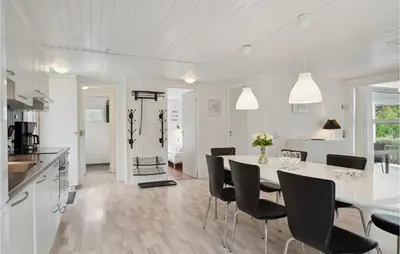 a white kitchen and dining room with a table and chairs at Cozy Home In Farsø With Sauna in Farsø