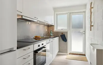 a kitchen with white cabinets and a window at Nice Apartment In Blokhus With Wifi in Blokhus