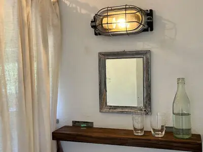 a mirror and two glasses on a shelf with a bottle at The Old Soap House - stylish and close to beach in Vang