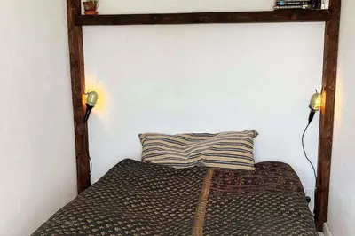 a bed with a wooden frame and a pillow on it at The Old Soap House - stylish and close to beach in Vang