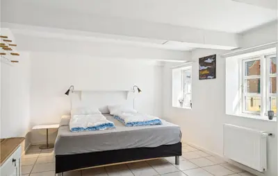 a white bedroom with a bed and two windows at Beautiful Home In Thyborøn With Sauna in Thyborøn