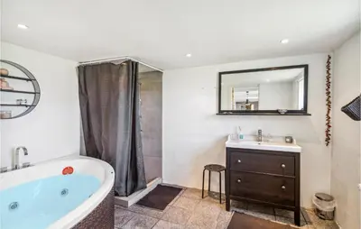 a bathroom with a tub and a sink and a mirror at Beautiful Home In Thyborøn With Sauna in Thyborøn