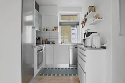 a white kitchen with white appliances and a window at Apartment in central Holstebro in Holstebro