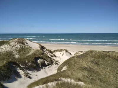 a beach with rocks and the ocean in the background at 6 person holiday home in Pandrup-By Traum in Pandrup