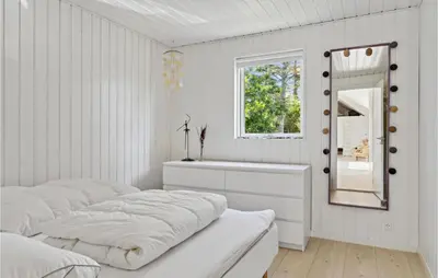 a white bedroom with two beds and a mirror at Nice Home In Blokhus With Kitchen in Blokhus