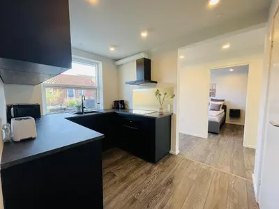 a kitchen with black counter tops and a living room at aday - Elegant Apartment with Terrace in Svenstrup
