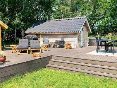 a dog laying on a wooden deck next to a cabin at 4 person holiday home in Thisted-By Traum in Thisted
