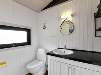 a bathroom with a toilet and a sink and a mirror at Holiday Home Riitta - 300m from the sea by Interhome in Løkken