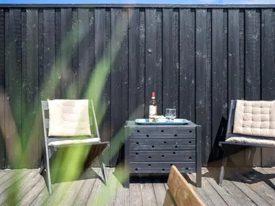a deck with two chairs and a table and a bottle of alcohol at Holiday Home Ilmari - 190m from the sea by Interhome in Pandrup