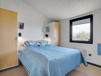 a bedroom with a blue bed with a window at Holiday Home Ilmari - 190m from the sea by Interhome in Pandrup