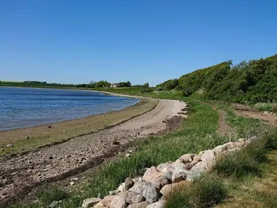 a rocky beach with a rock wall next to the water at 5 person holiday home in Karby-By Traum in Karby