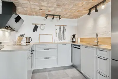 a kitchen with white cabinets and a wooden ceiling at Feriehuset Hygge ved Fjorden in Thyholm