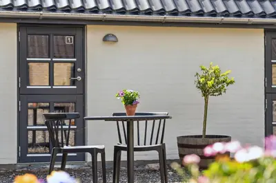a patio with two chairs and a table with flowers at Feriehuset Hygge ved Fjorden in Thyholm