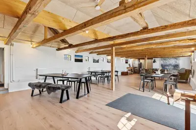 a room with tables and chairs and wooden ceilings at Feriehuset Hygge ved Fjorden in Thyholm