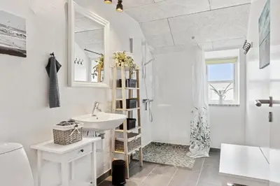 a white bathroom with a sink and a shower at Feriehuset Hygge ved Fjorden in Thyholm