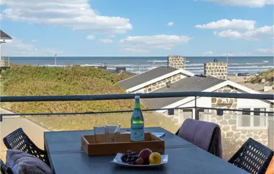 a table with a bottle and a bowl of fruit on a balcony at Beautiful Home In Blokhus in Blokhus