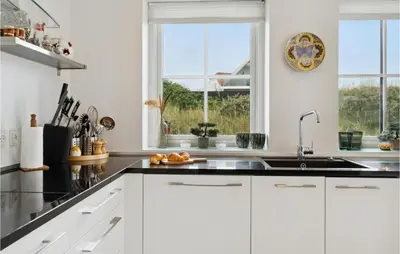 a kitchen with white cabinets and a sink at Beautiful Home In Blokhus in Blokhus
