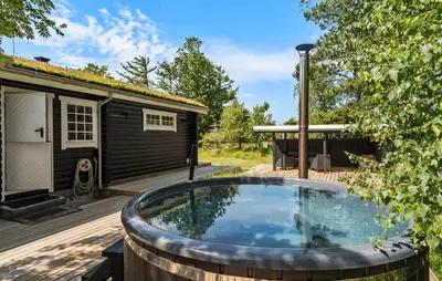 a hot tub on a deck next to a house at Lovely Home In Højslev With Kitchen in Lundø