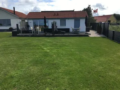 a house with a yard with chairs and a porch at Casa Uno North - Nice appartement for two with sea view in Farsø