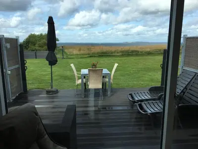 a deck with a table and chairs and an umbrella at Casa Uno North - Nice appartement for two with sea view in Farsø