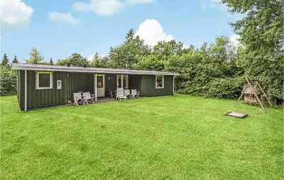 a green house with a yard with chairs and a playground at Holiday Home Illeris Farsø Vi in Farsø