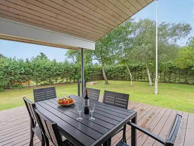 a table with a bottle of wine and a bowl of fruit at Holiday Home Ønder - 800m from the sea by Interhome in Blokhus