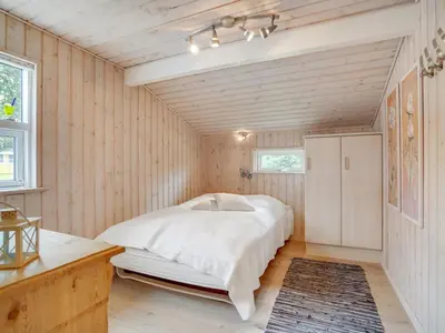 a bedroom with a bed in a room with wooden walls at Holiday Home Ønder - 800m from the sea by Interhome in Blokhus