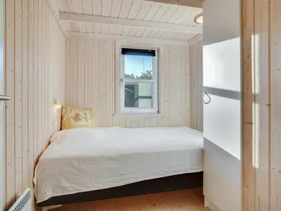 a small bedroom with a bed and a window at Holiday Home Gun - 450m from the sea by Interhome in Blokhus