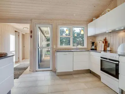 a kitchen with white cabinets and a large window at Holiday Home Gun - 450m from the sea by Interhome in Blokhus