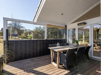 a patio with a table and chairs on a deck at Holiday Home Gun - 450m from the sea by Interhome in Blokhus