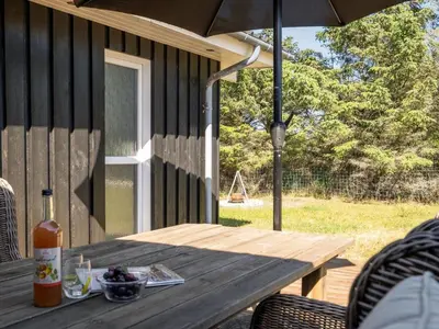 a wooden table with an umbrella on a patio at Holiday Home Gun - 450m from the sea by Interhome in Blokhus