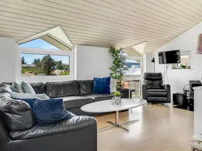 a living room with a leather couch and a table at Holiday Home Jenvold - 600m from the sea by Interhome in Torsted