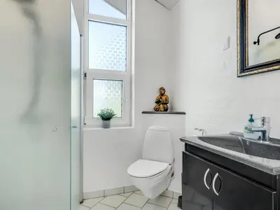 a bathroom with a toilet and a sink and a window at Holiday Home Jenvold - 600m from the sea by Interhome in Torsted