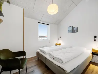 a bedroom with a bed and a chair at Holiday Home Ivar - 300m from the sea by Interhome in Harboør