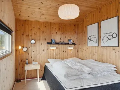 a bedroom with a bed in a wooden wall at Holiday Home Wolter - 700m from the sea by Interhome in Harboør