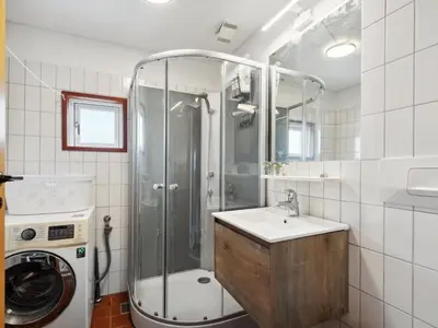 a bathroom with a shower and a sink and a washing machine at Holiday Home Wolter - 700m from the sea by Interhome in Harboør