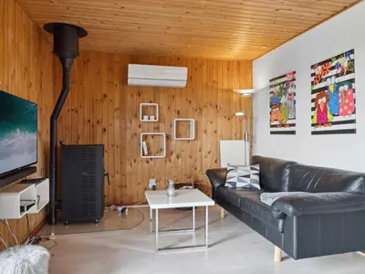 a living room with a black leather couch and wooden walls at Holiday Home Wolter - 700m from the sea by Interhome in Harboør
