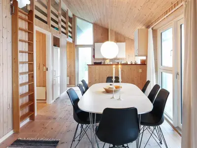 a dining room with a white table and black chairs at Holiday Home Ilkka - 400m from the sea by Interhome in Torsted