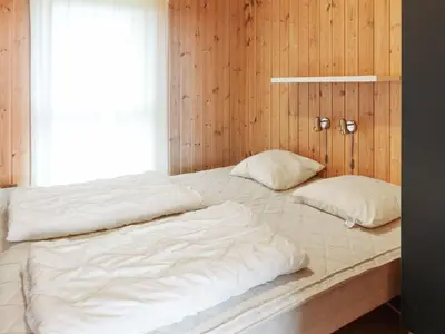a bed with two pillows on it in a room at Holiday Home Ilkka - 400m from the sea by Interhome in Torsted