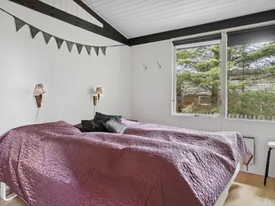 a bedroom with a bed with a purple comforter and a window at Holiday Home Velika - 1-2km from the sea by Interhome in Thisted