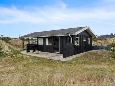 a black house with a wooden porch on a beach at Holiday Home Sulo - 1-4km from the sea by Interhome in Torsted