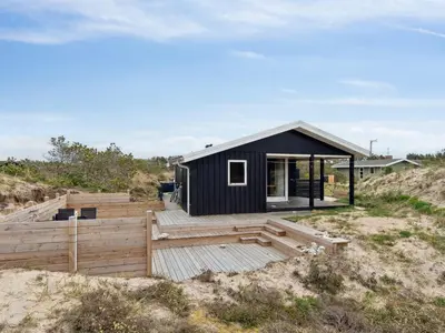 a black house on the beach with a wooden deck at Holiday Home Sulo - 1-4km from the sea by Interhome in Torsted