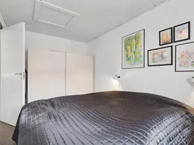 a bedroom with a bed with white cabinets and pictures at Holiday Home Ubbe - 200m from the sea by Interhome in Lemvig